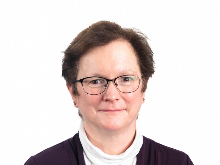 Headshot of Shelley Brundage standing in front of a blank background. 